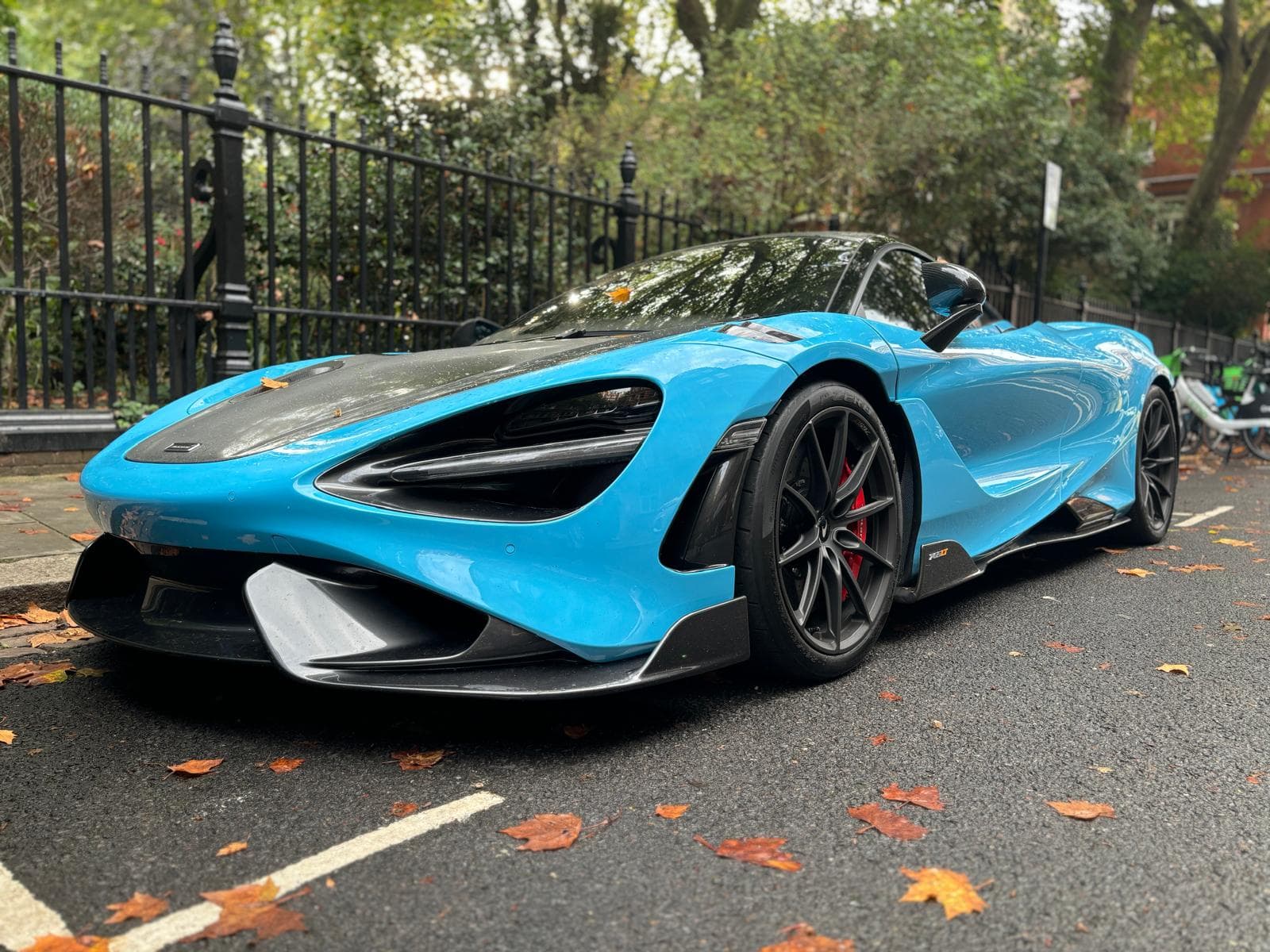 Turquoise McLaren supercar parked on a leafy London street